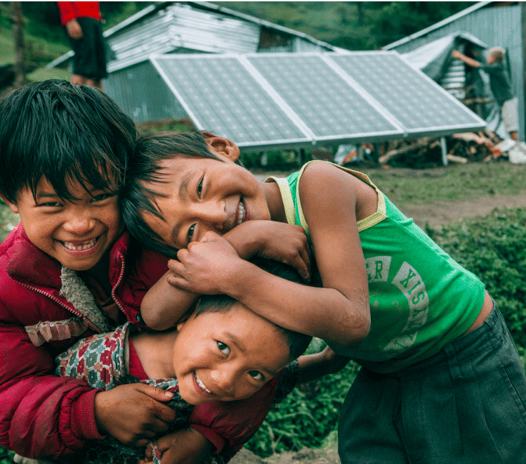 village children playing in front of donated solar panels